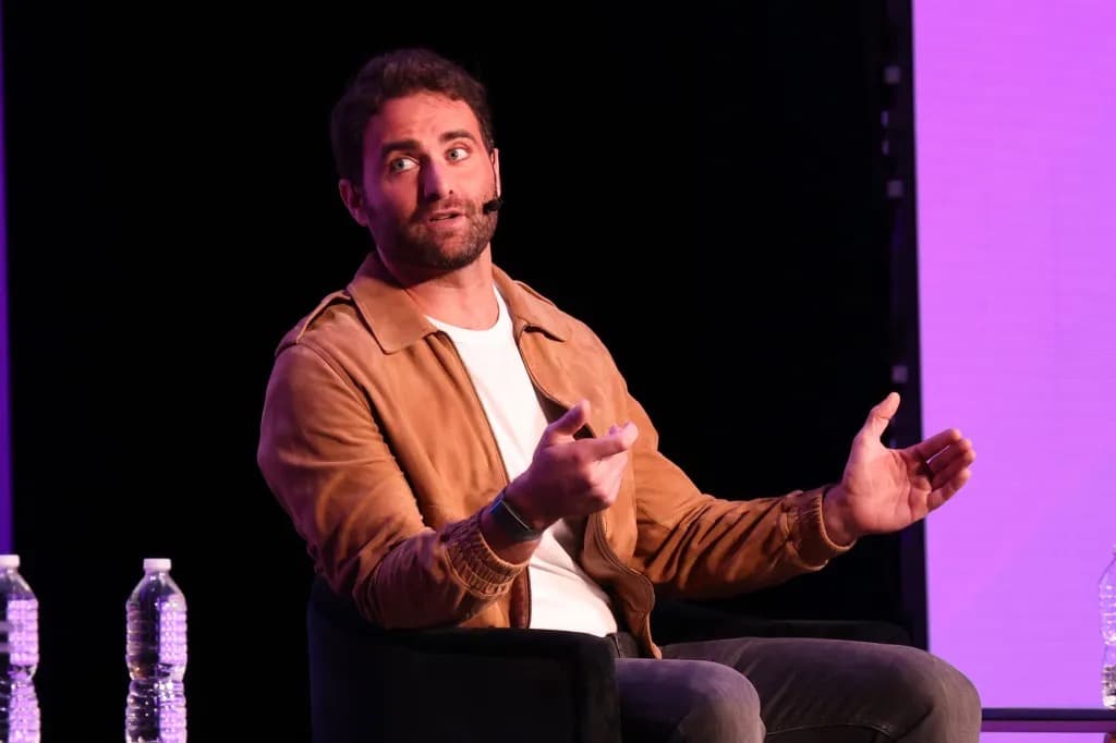 Peter Rahal, CEO of David Protein, speaking on stage in a tan jacket