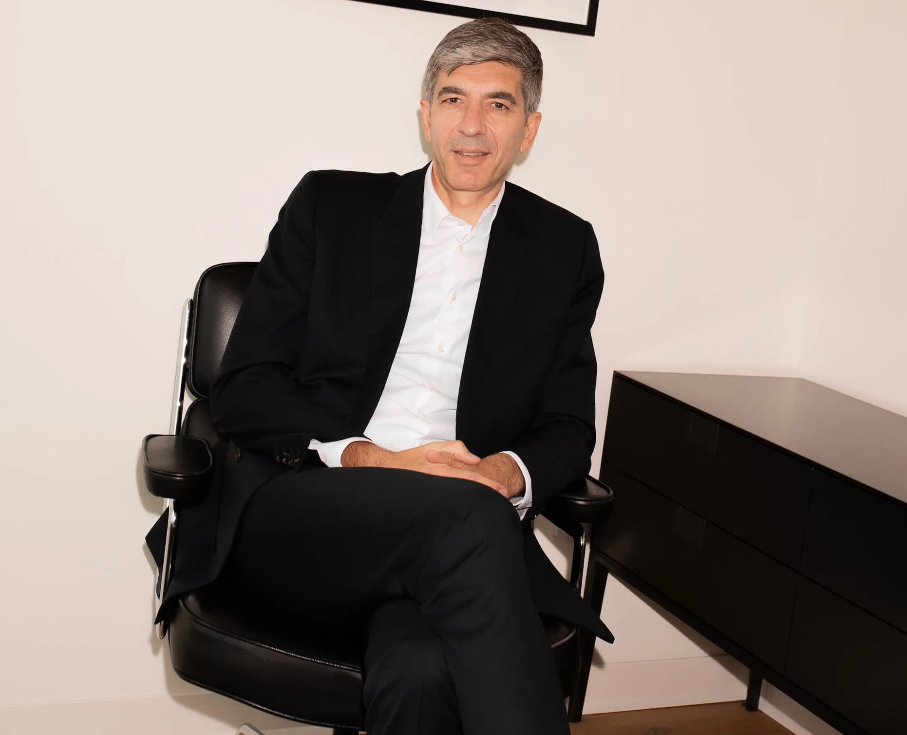 Gianfranco D'Attis seated in a black leather chair wearing a black blazer