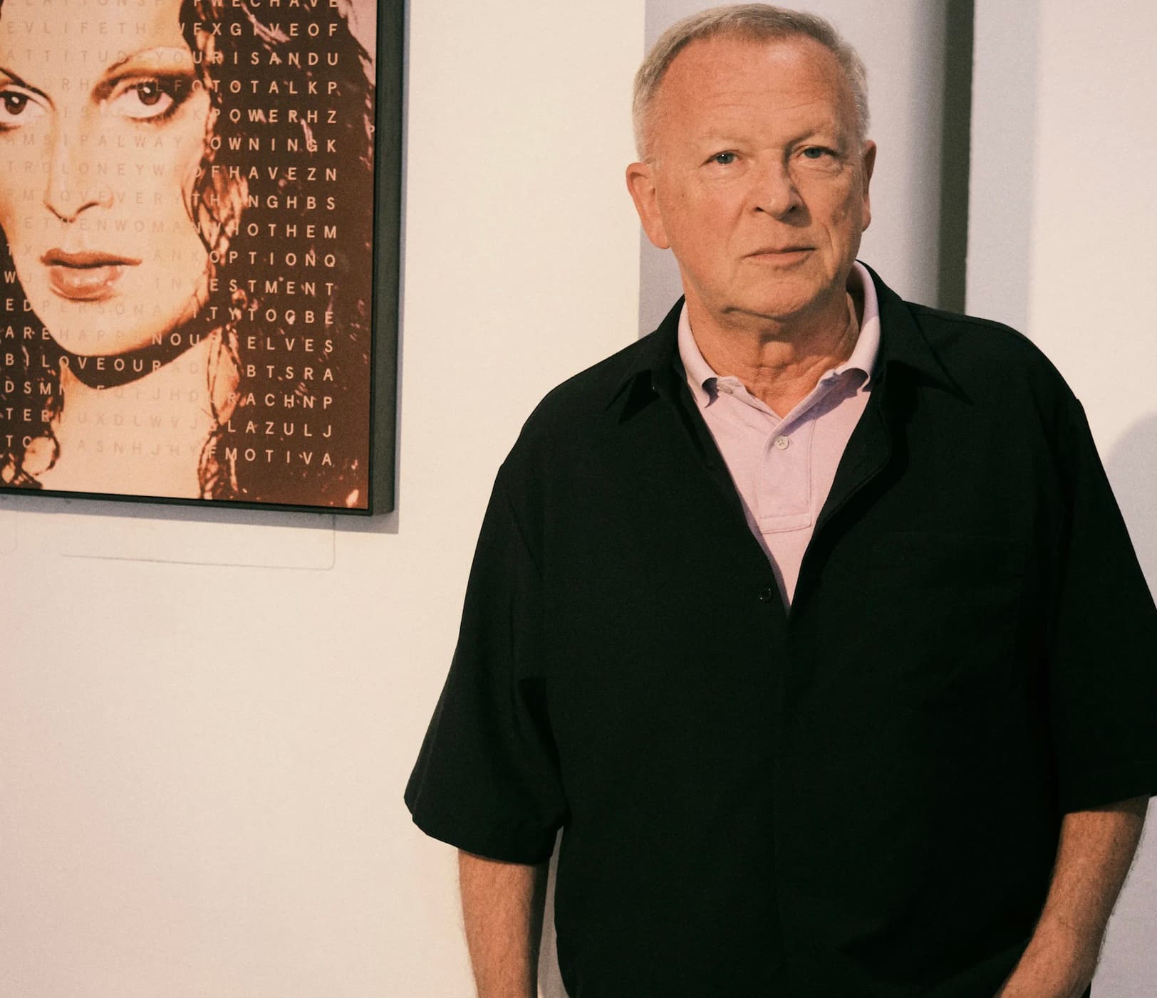 Graziano de Boni standing beside a framed portrait artwork in a gallery setting