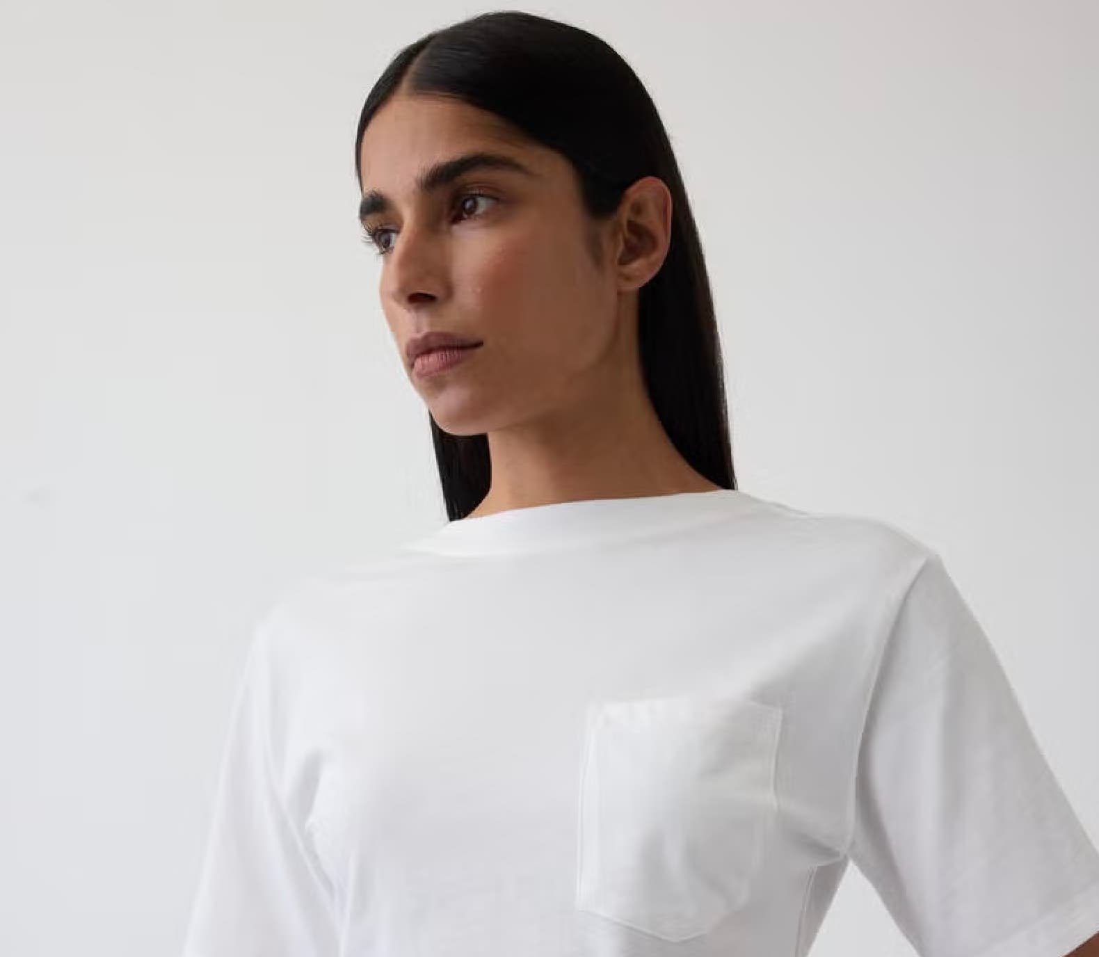 A model wearing a crisp white GapStudio pocket tee against a pale studio backdrop