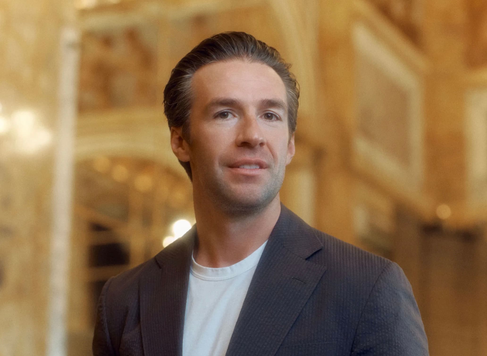 Michael Murray in a dark blazer standing in an ornate gold interior