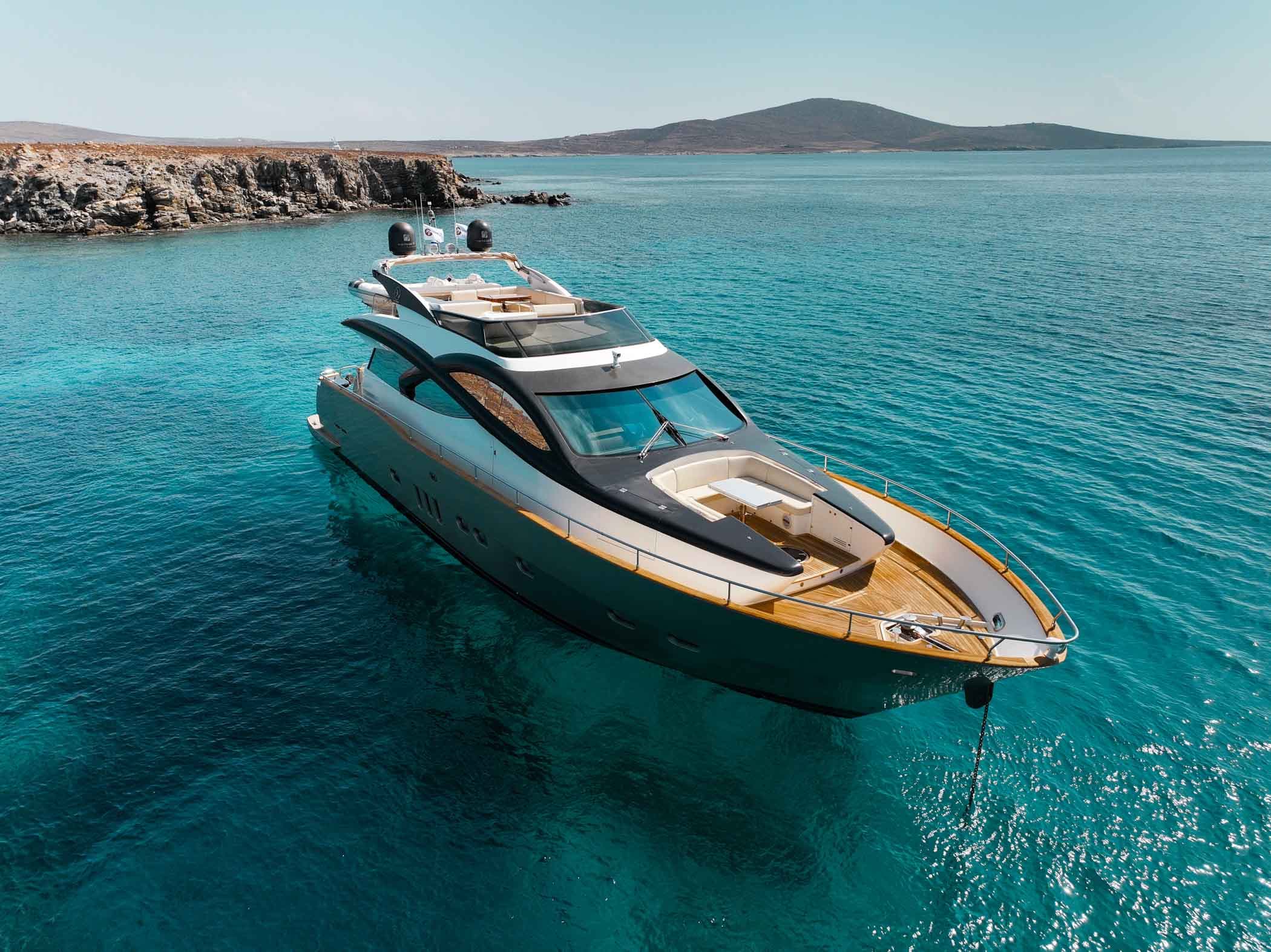 A luxury yacht anchored in a turquoise cove off the coast of Mykonos in the Cyclades