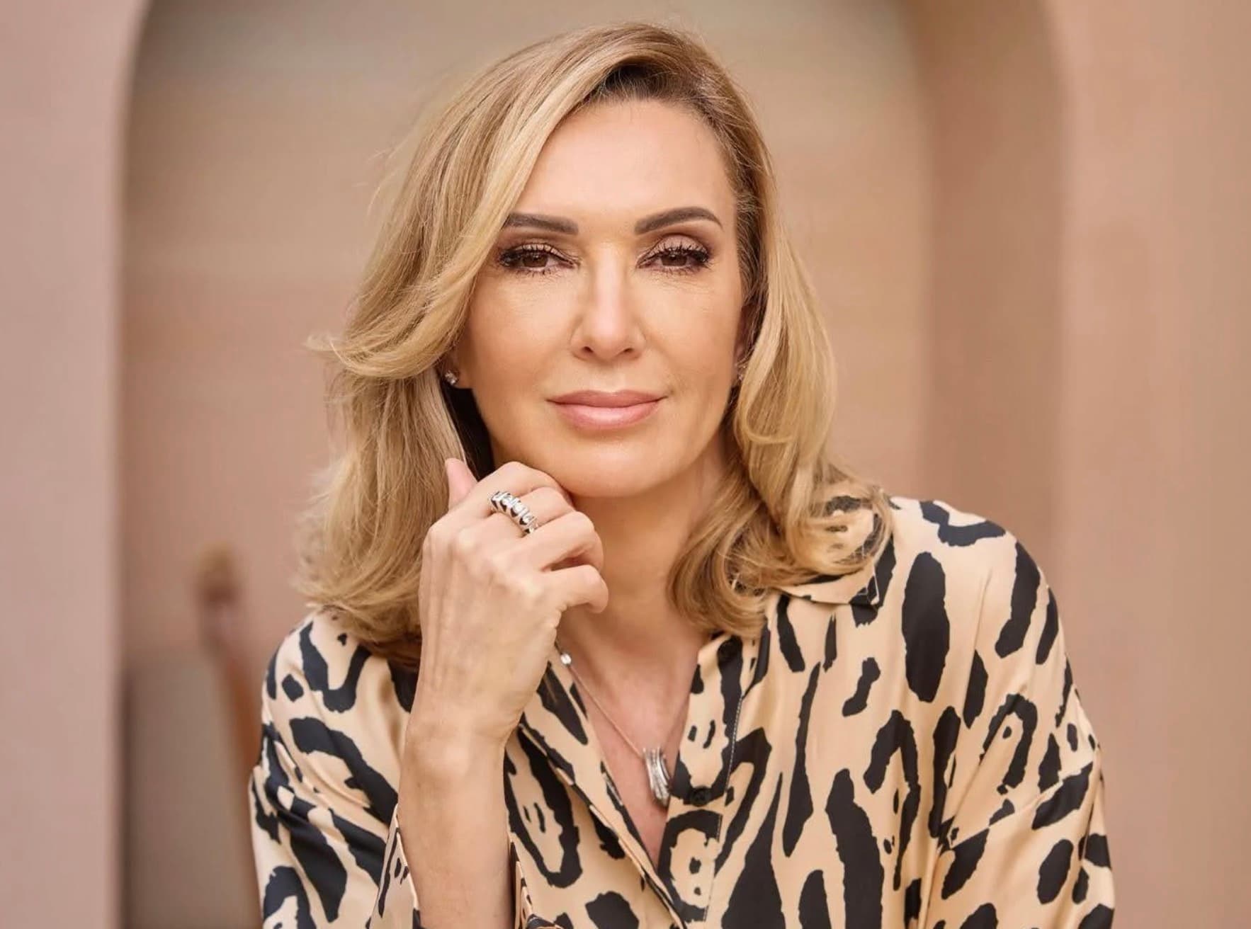 Sabrina Carbone, luxury wedding planner, in a leopard print blouse against a warm arch
