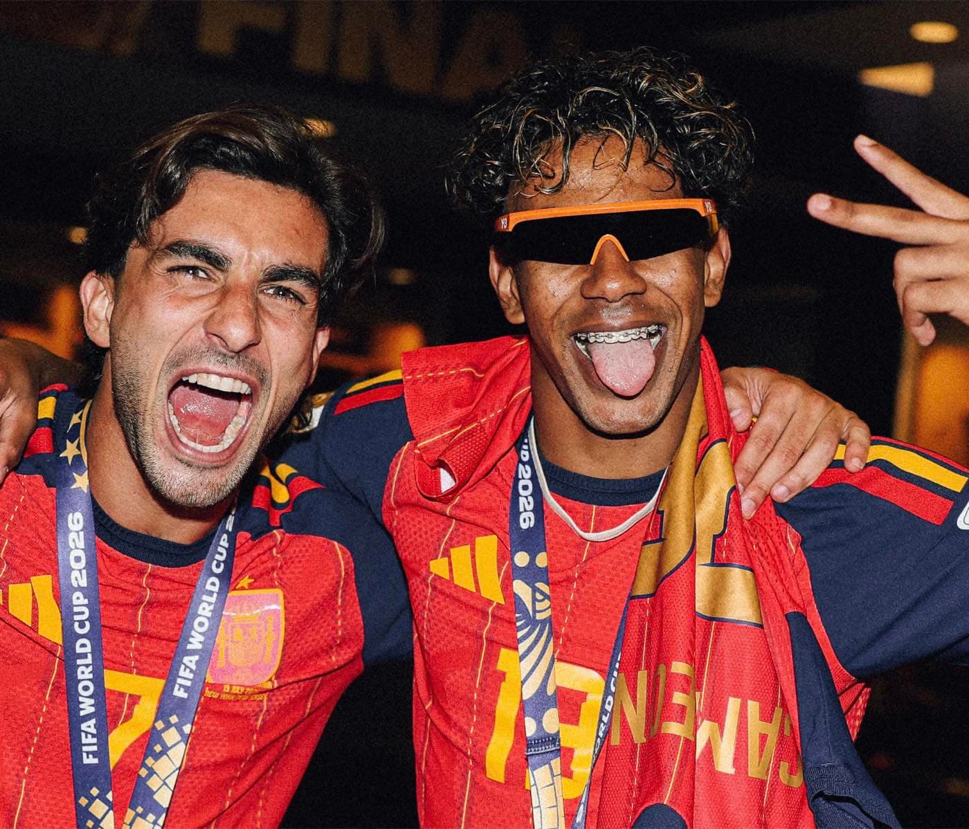 Two footballers in red Adidas Spain kit celebrating with World Cup 2026 final medals