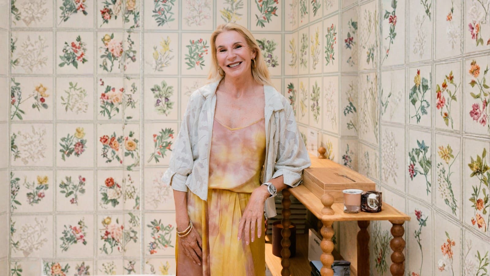 Film producer Christel Henon smiling in a yellow dress against a floral tiled wall