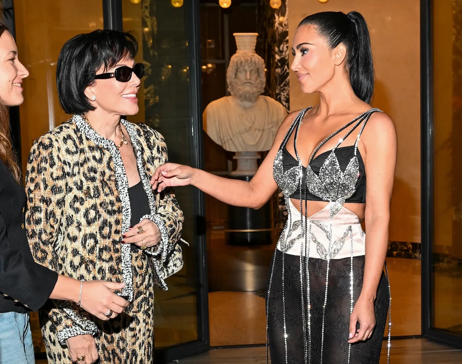 Kim Kardashian in a crystal embellished top talking with Kris Jenner in a leopard print tweed suit