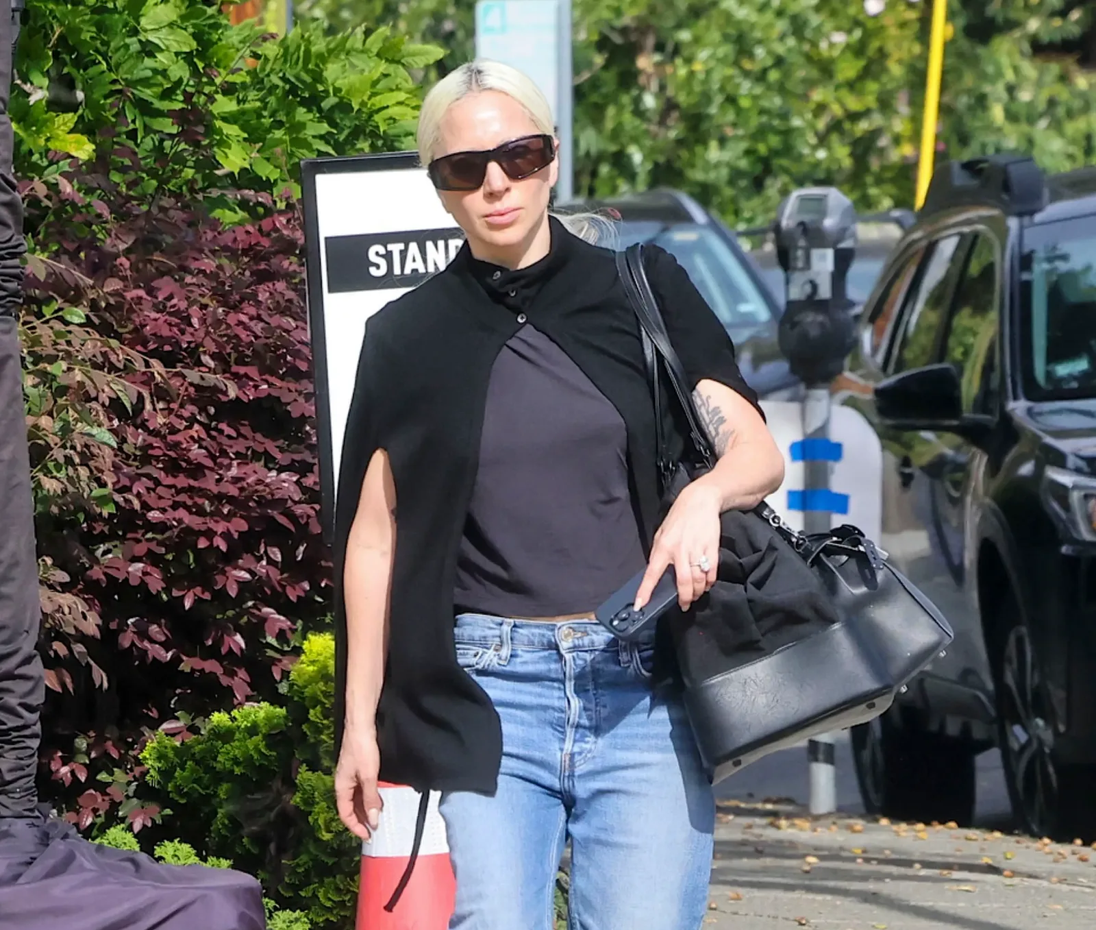 Lady Gaga wearing a black cape top, jeans, and sunglasses while out running errands