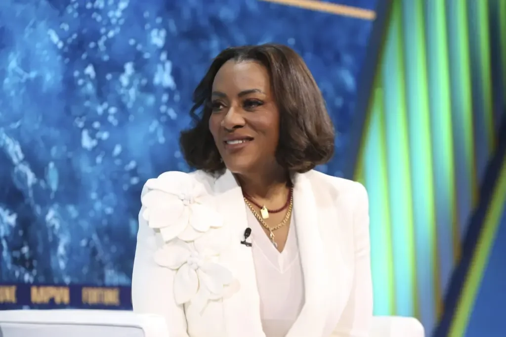 Latriece Watkins smiling in a white floral-detail blazer during a Fortune interview