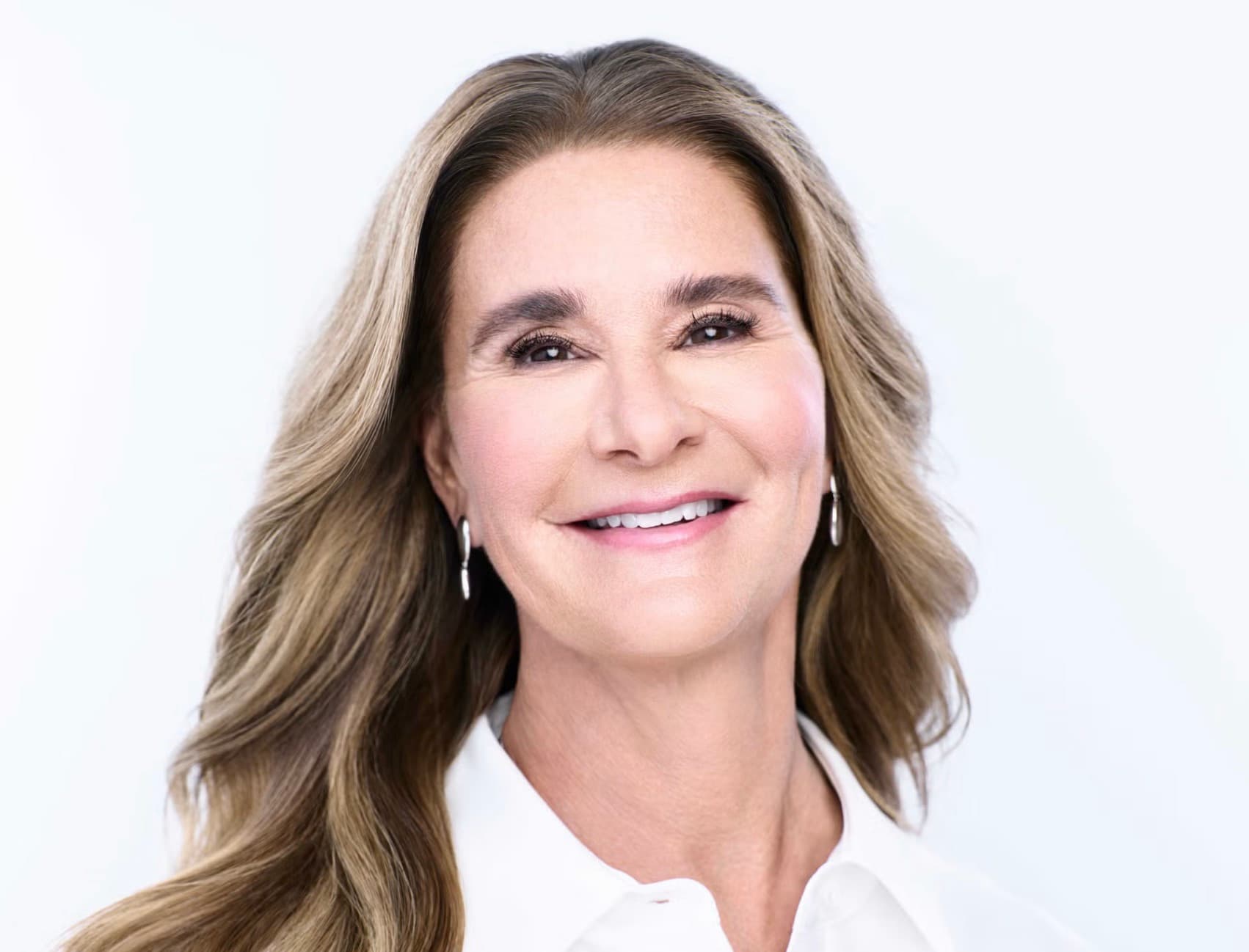 Melinda French Gates smiling in a white shirt against a white background