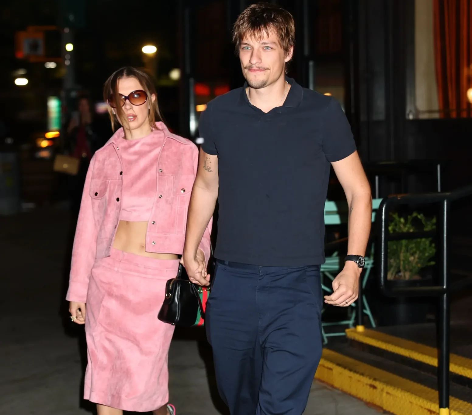 Millie Bobby Brown and Jake Bongiovi holding hands while walking at night in New York