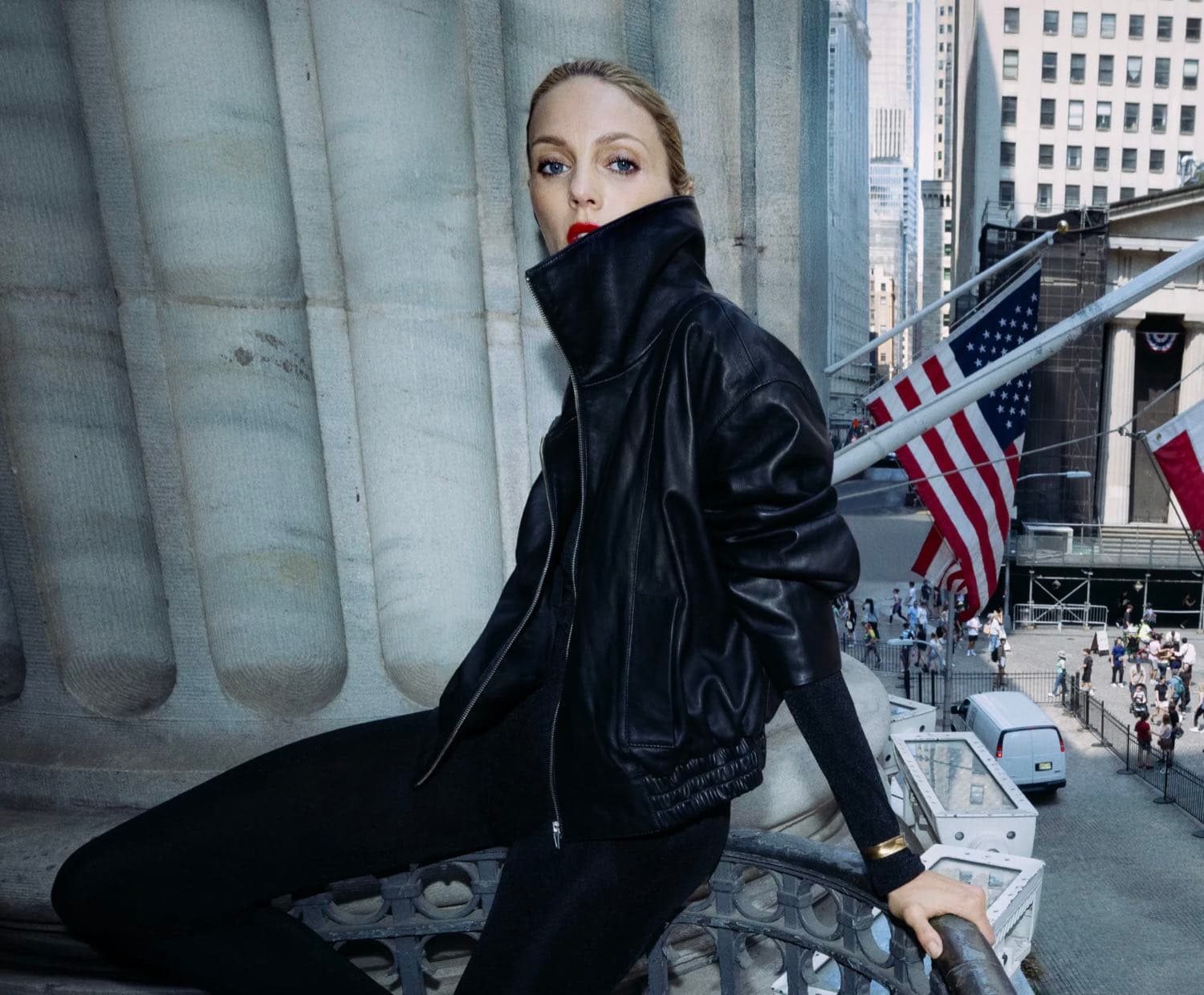 A model in a black leather jacket and red lip posed on the steps of a Wall Street building